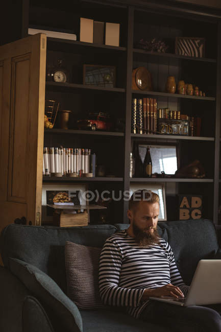 Чоловік сидить на дивані, використовуючи свій ноутбук — стокове фото