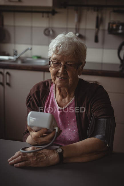 Femme âgée vérifiant sa tension artérielle à la maison — Photo de stock