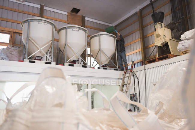 Чоловік кладе зерно в елеватор на заводі — стокове фото