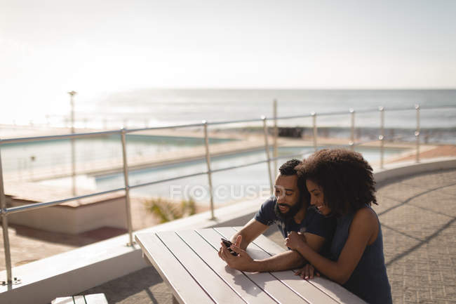 Paar benutzt Handy an einem sonnigen Tag auf der Promenade — Stockfoto