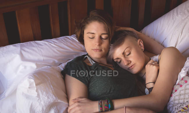 Lesbian couple cuddling while sleeping on bed in bedroom at home. — Stock Photo
