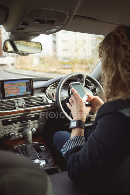 Задний вид женщины-руководителя с помощью мобильного телефона в автомобиле — стоковое фото