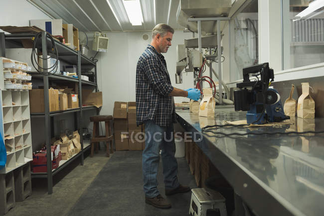Mann verpackt Getreide mit Maschine in Fabrik — Stockfoto