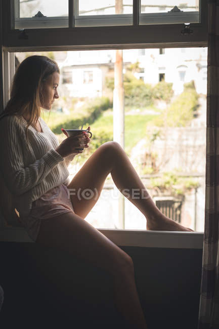 Frau sitzt bei offenem Fenster beim Kaffee zu Hause. — Stockfoto
