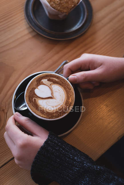 Overhead of woman having cappuccino at table in cafe — Stock Photo