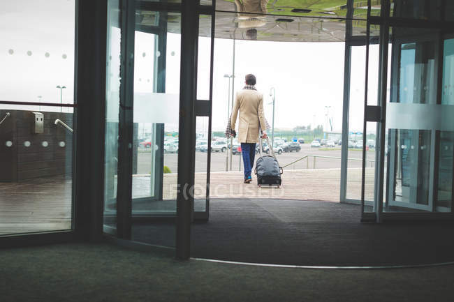 Vista traseira do empresário saindo do hotel com bagagem — Fotografia de Stock