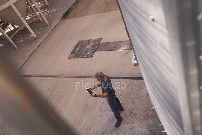 Vue grand angle de l'homme en utilisant une tablette numérique dans l'usine — Photo de stock