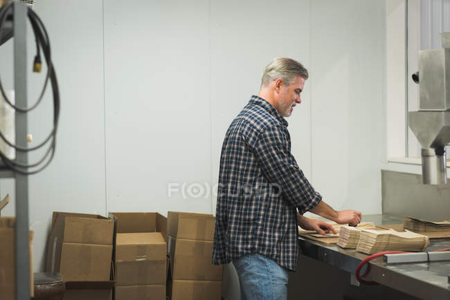 Человек готовит картонную коробку на заводе — стоковое фото