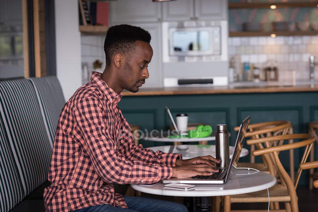 Male office executive using laptop in cafeteria at creative office — Stock Photo