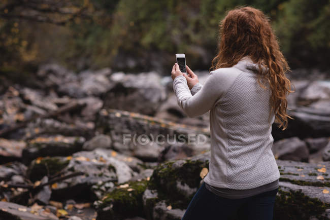 Vista trasera de la mujer tomando fotos de la montaña con el teléfono móvil - foto de stock