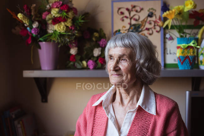 Усміхнена старша жінка сидить в будинку догляду — стокове фото