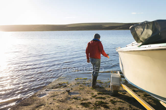 Чоловік перевіряє моторний човен біля берега річки . — стокове фото