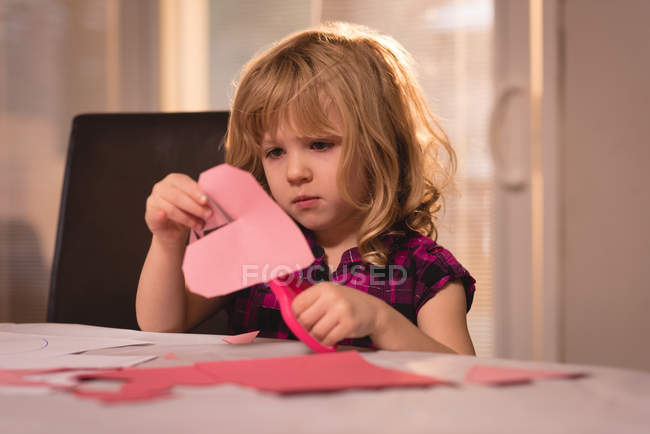 Girl preparing heart shape decoration with craft paper at home — Stock Photo