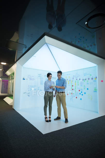 Executivos masculinos e femininos usando tablet digital em escritório futurista — Fotografia de Stock