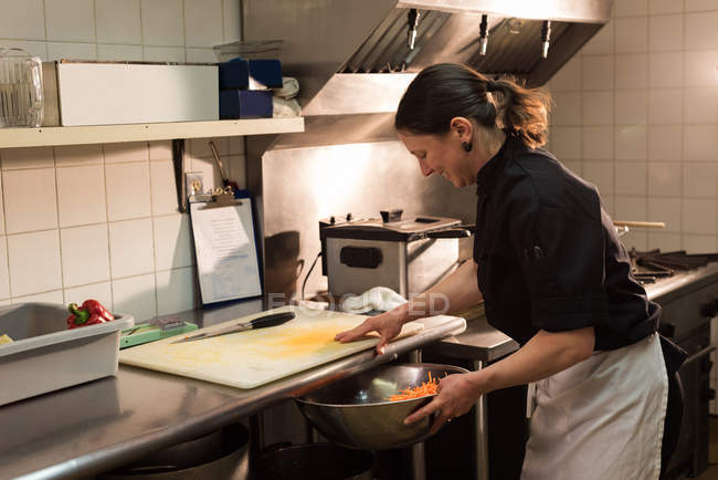 Koch legt gehacktes Gemüse in die große Schüssel in der Küche — Stockfoto