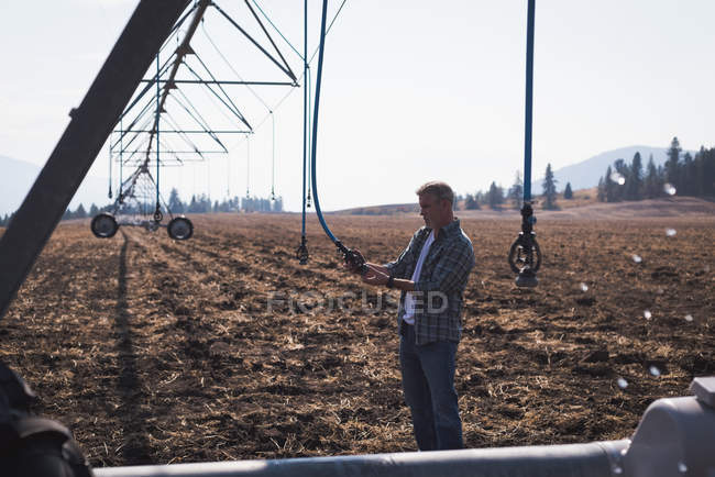 Agricultor que verifica o sistema de irrigação automatizado no campo — Fotografia de Stock