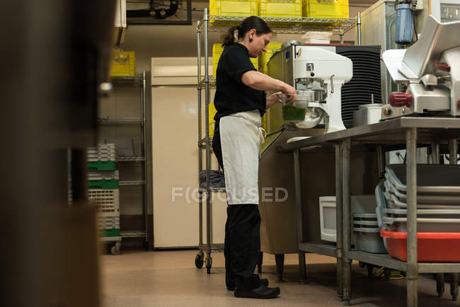 Chef mezclando la comida en la máquina en la cocina - foto de stock