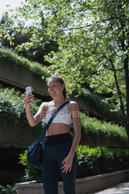Счастливая спортивная женщина делает видеозвонок по мобильному телефону на улице — стоковое фото