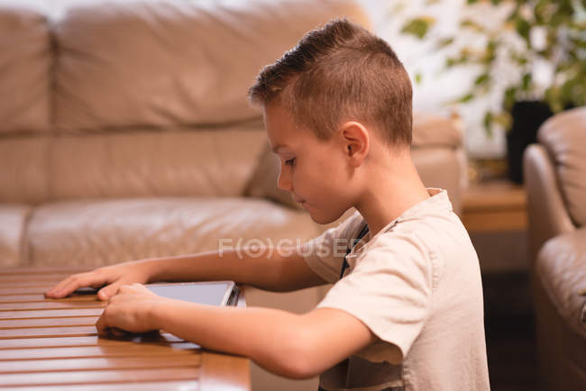 Garçon utilisant tablette numérique dans le salon à la maison — Photo de stock