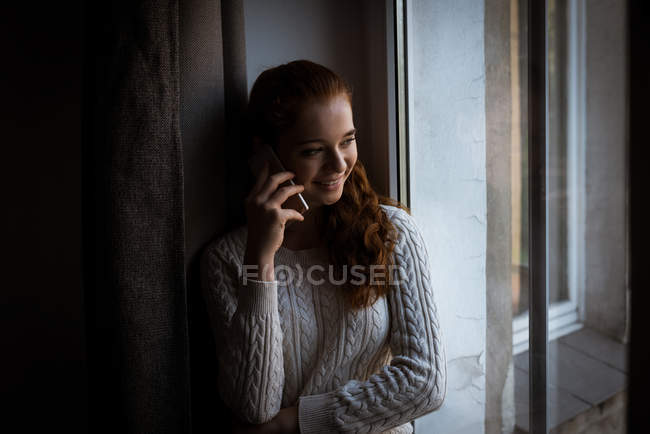 Lächelnder Teenager, der zu Hause mit dem Handy spricht — Stockfoto