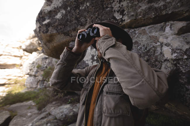 Wanderer blickt aus der Höhle durch Ferngläser — Stockfoto