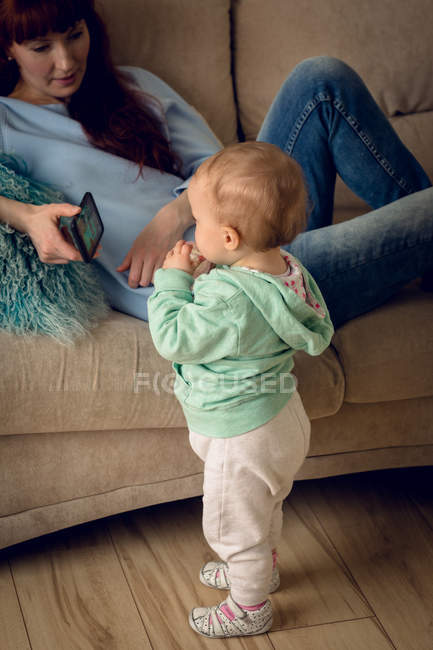 Mãe mostrando telefone celular para bebê menina em casa — Fotografia de Stock