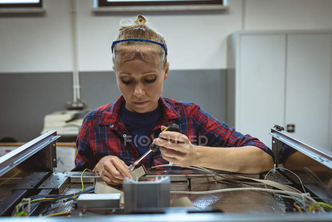 Lavoratrice che ripara una macchina con utensile in fabbrica — Foto stock