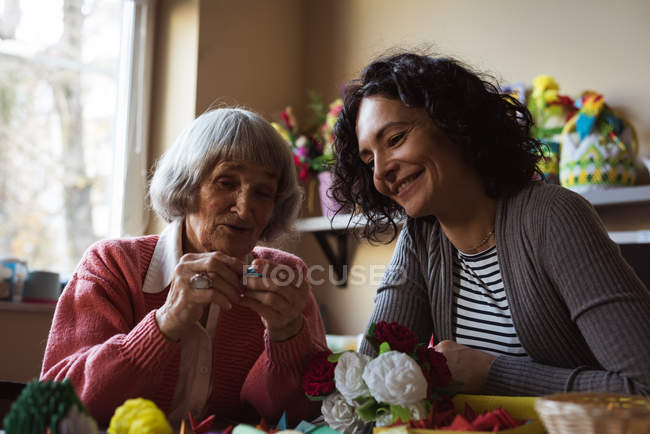 Улыбающаяся пожилая женщина, взаимодействующая со смотрителем в доме престарелых — стоковое фото