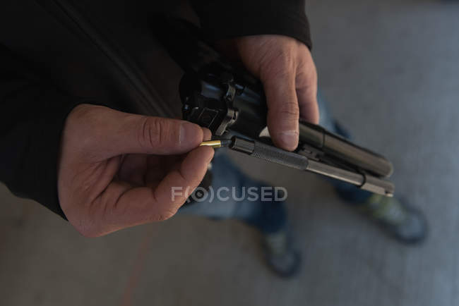 Крупним планом людина заряджає кулю в пістолет — стокове фото