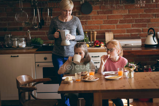 Grandmother serving breakfast to granddaughters in kitchen — Stock Photo