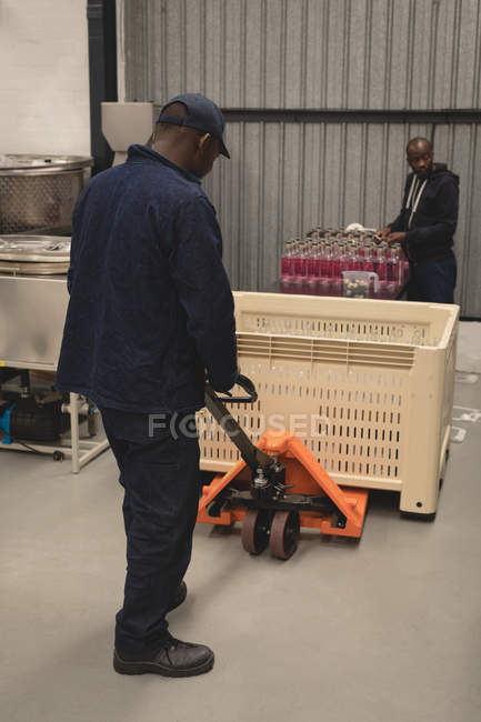 Lavoratori che caricano bottiglie di gin nel jack per pallet in fabbrica — Foto stock