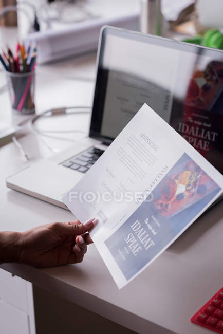 Close-up of businessperson holding a brochure at desk — Stock Photo