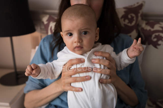 Портрет милий маленька дитина дивиться в камеру і мама тримала його в центр hom — стокове фото