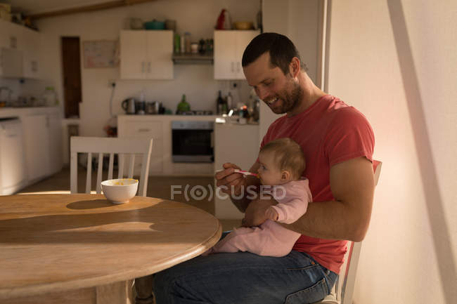 Père nourrissant bébé garçon avec cuillère à la maison . — Photo de stock