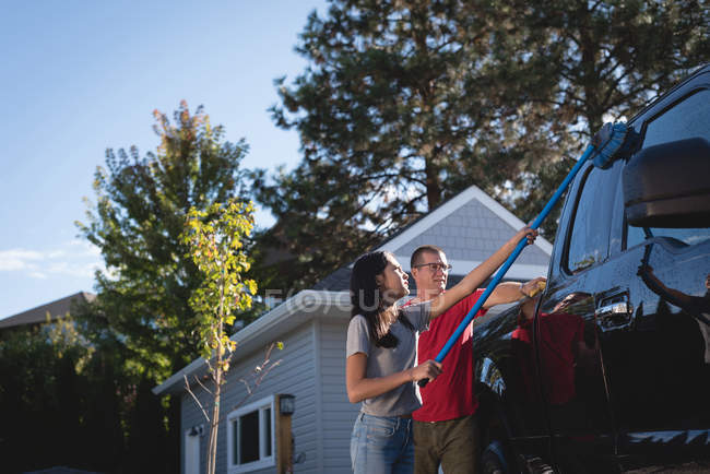 Отец и дочь моют машину у гаража — стоковое фото