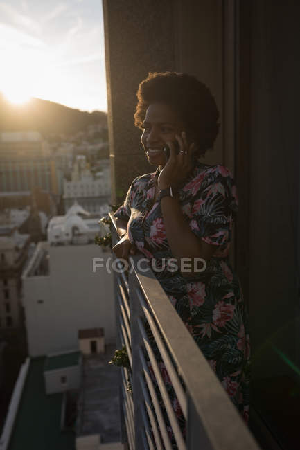 Woman talking on mobile phone in balcony at home. — Stock Photo