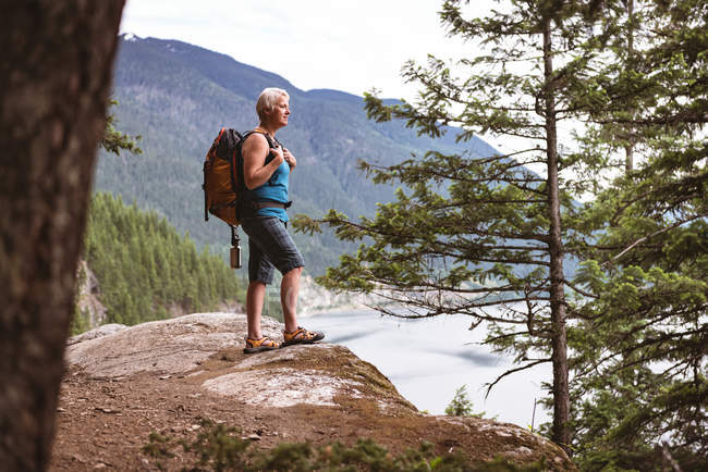 Side view of mature woman standing on rock in the forest — Stock Photo