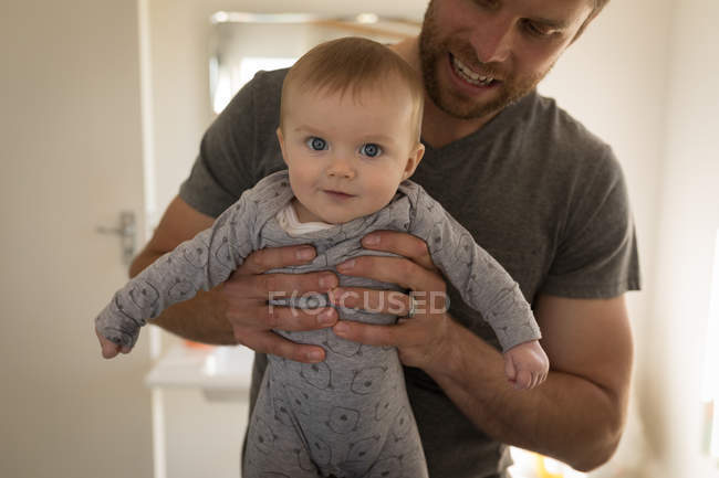 Father holding baby boy at home, close-up. — Stock Photo