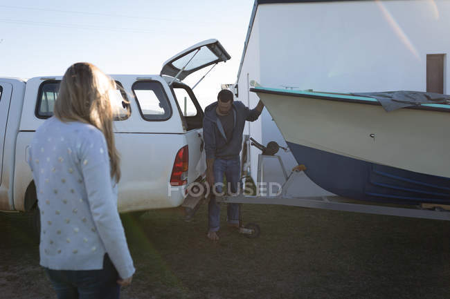 Man connecting motorboat to car truck outdoors in sunlight. — Stock Photo