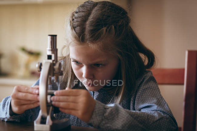 Fille mignonne expérimentant avec microscope à la maison — Photo de stock