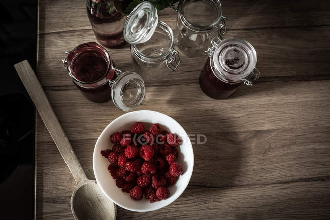 Ciotola di lamponi con marmellata sul tavolo di legno a casa — Foto stock