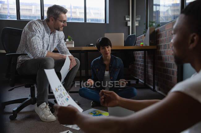 Ділові колеги обговорюють документи на підлозі в офісі . — стокове фото