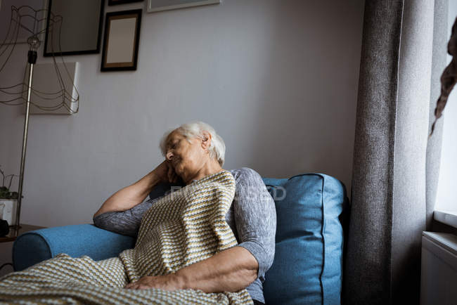 Senior mulher relaxante na poltrona na sala de estar em casa — Fotografia de Stock