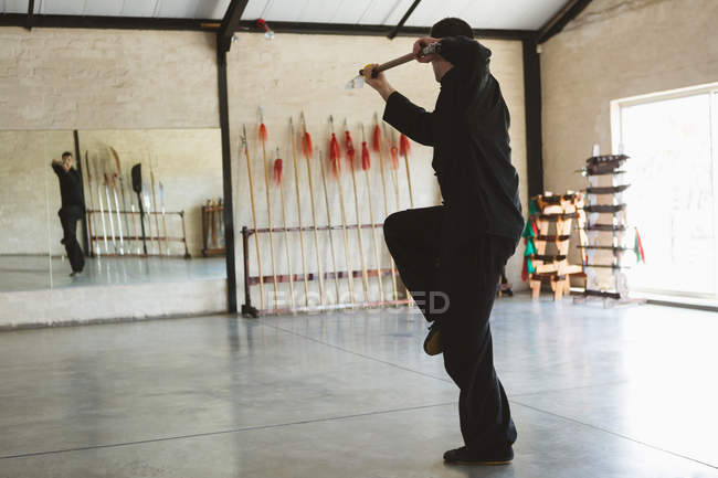Karate fighter practicing with long pole in fitness studio. — Stock Photo