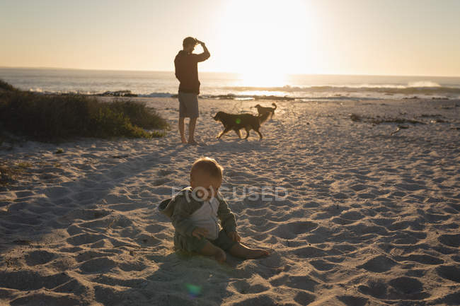Bébé garçon jouant dans le sable à la plage pendant le coucher du soleil — Photo de stock