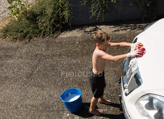 Ragazzo che lava un'auto in un garage esterno in una giornata di sole — Foto stock