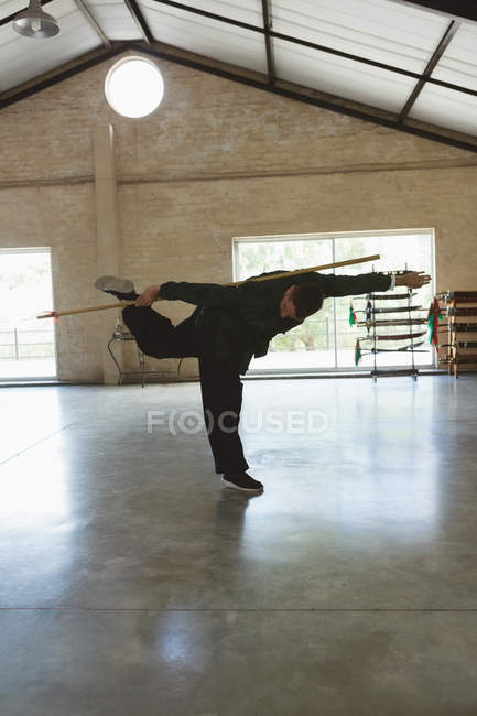 Luchador de karate practicando con bastón largo en gimnasio . - foto de stock