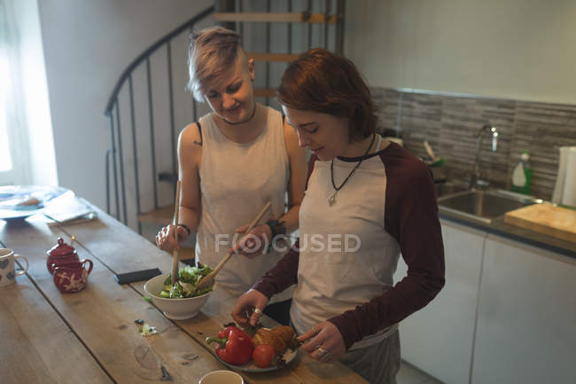 Couple lesbien préparant la salade dans la table de cuisine à la maison . — Photo de stock