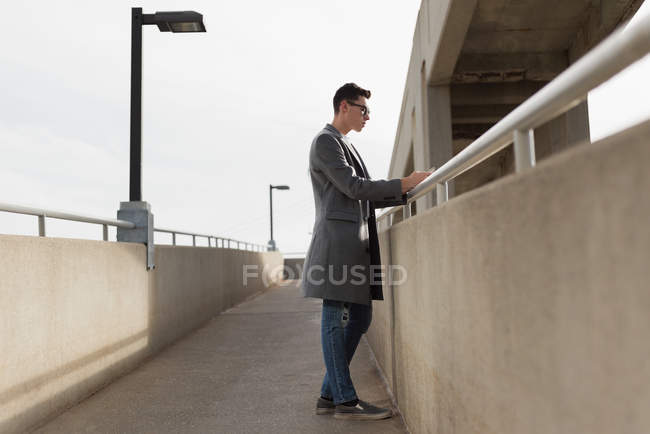 Hombre reflexivo usando el teléfono móvil en el puente - foto de stock
