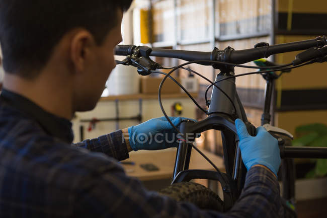 Visão traseira do homem reparando amortecedor de bicicleta na loja — Fotografia de Stock